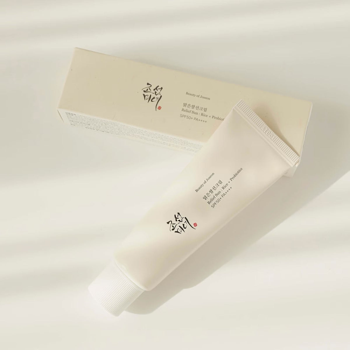 Beauty of Joseon Relief Sun : Rice + Probiotics SPF50+ PA++++ tube lying beside its cream-coloured carton box on a white background