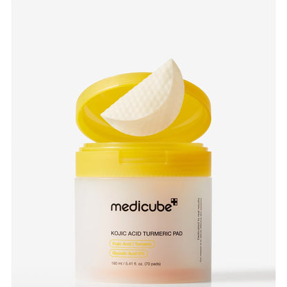 Open medicube Kojic Acid Turmeric Pad jar with a yellow flip lid and a single white textured toner pad resting on top.