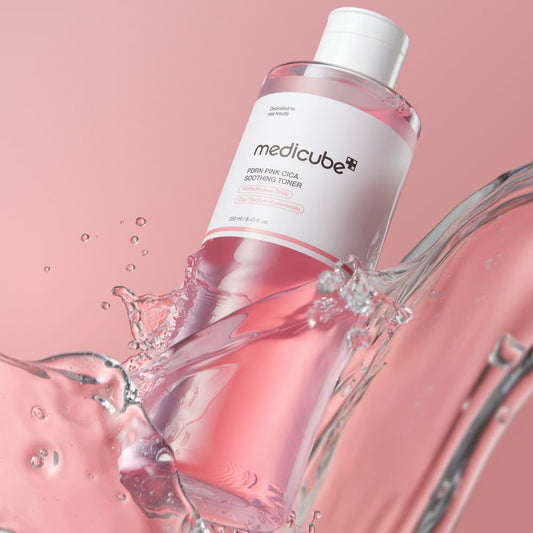 medicube PDRN Pink Cica Soothing Toner bottle surrounded by a pink water splash on a pink background