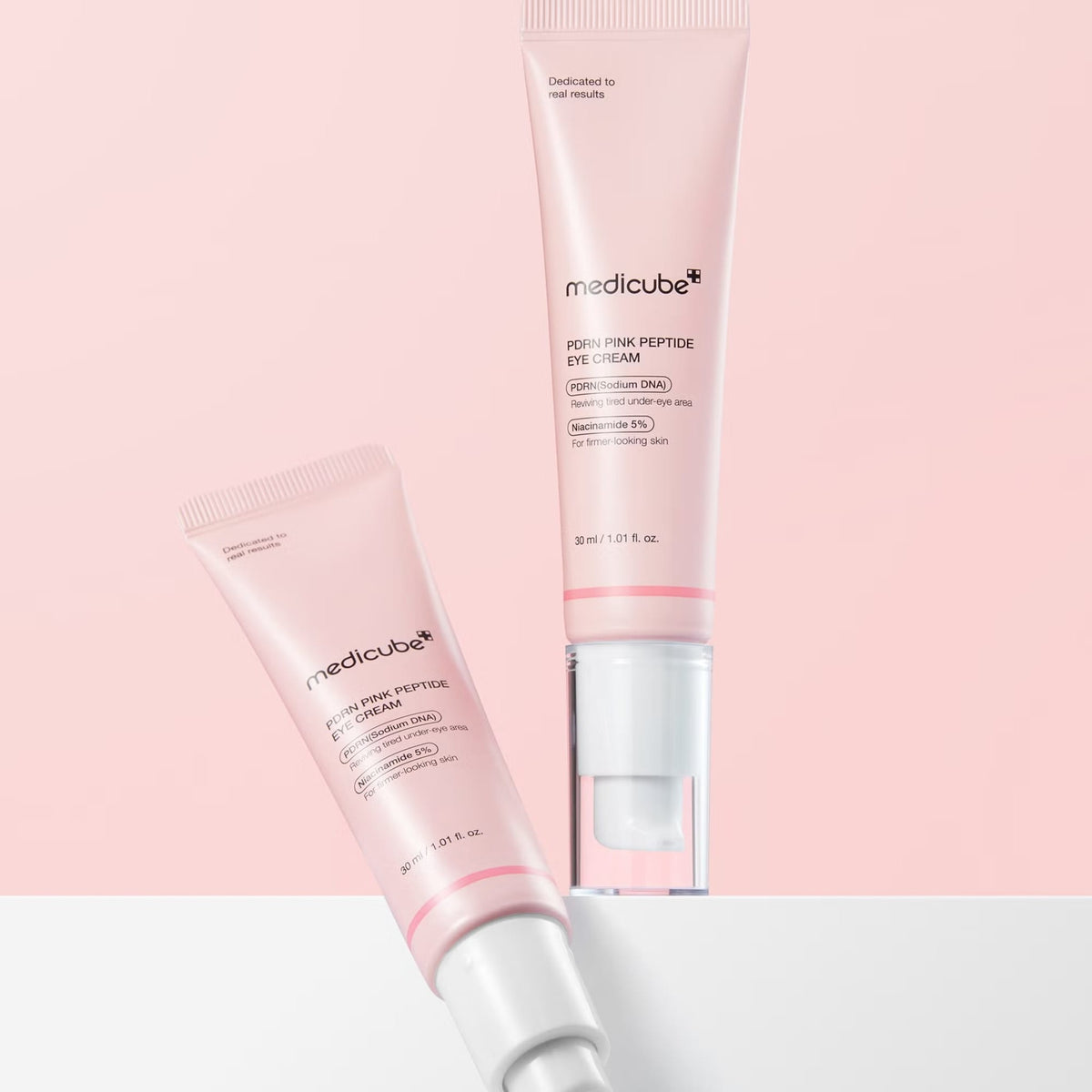 Two medicube PDRN Pink Peptide Eye Cream 30 ml tubes displayed diagonally on a pink background